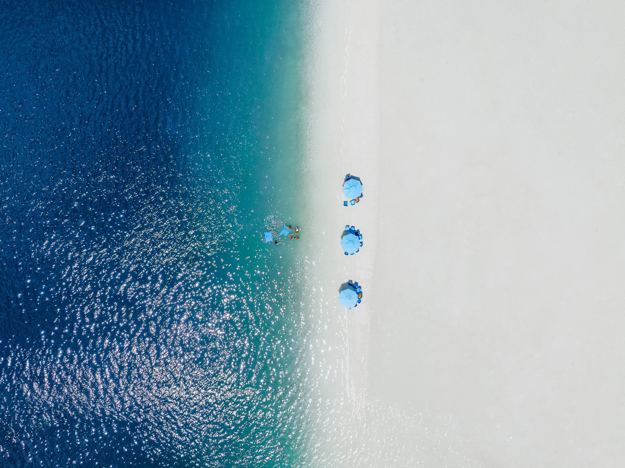 海水与白沙交界处的蓝色遮阳伞