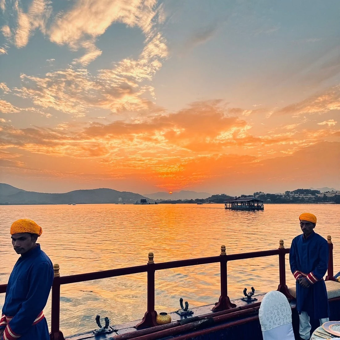 两位旅客站在湖畔欣赏橙色晚霞