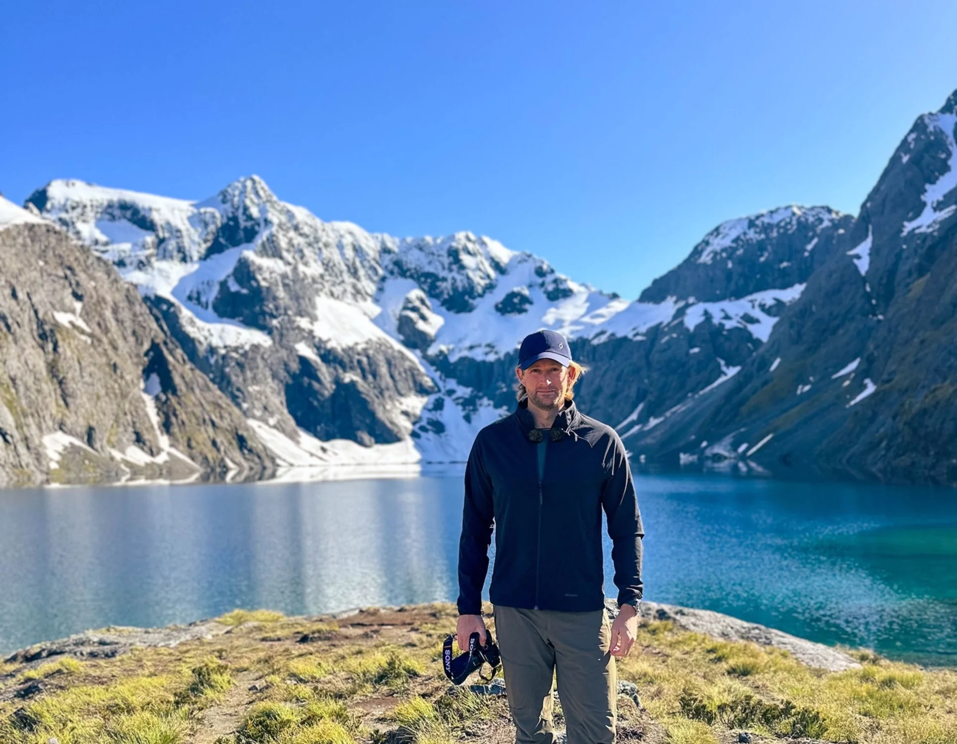 旅人站在高山湖泊旁的岩石岸边