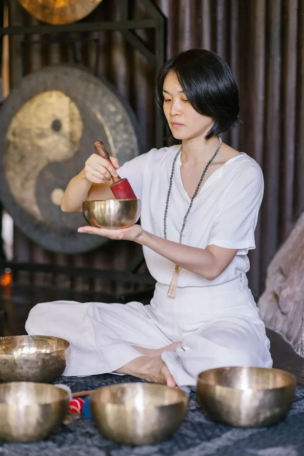 身穿浅色服装的护理人员正在敲击铜钵
