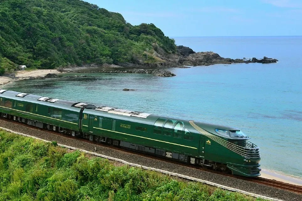 绿色列车沿海岸与林坡行驶